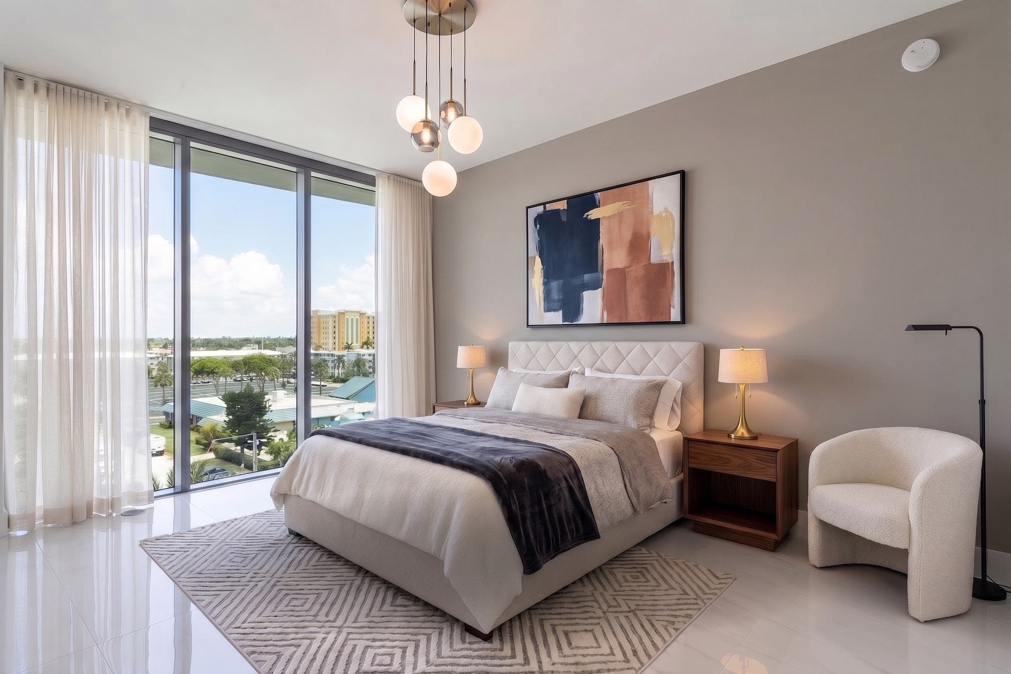The same bedroom restyled with a gray accent wall, abstract art, pendant lights and a patterned rug