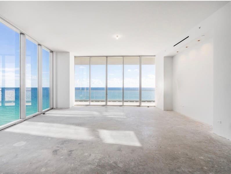 Unfinished oceanfront condo with bare concrete floors and floor-to-ceiling windows